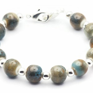 May include: A silver bracelet with blue and brown ceramic beads.