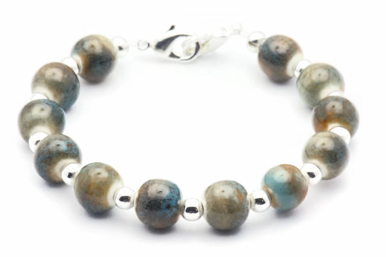 Pode incluir: Um bracelete de prata com contas de cer&acirc;mica azul e marrom.
