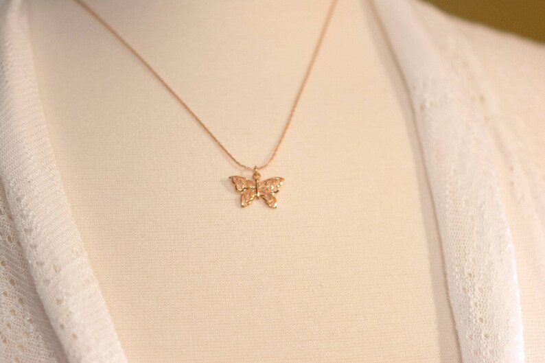 Peut inclure: Un collier en cha&icirc;ne dor&eacute;e avec un pendentif d&eacute;licat en forme de papillon.