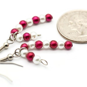 May include: A pair of earrings with alternating red and white beads. The earrings are made with small, round beads and have silver hooks.