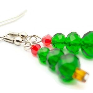 May include: Green and red crystal bead earrings shaped like Christmas trees. The earrings have silver hooks.