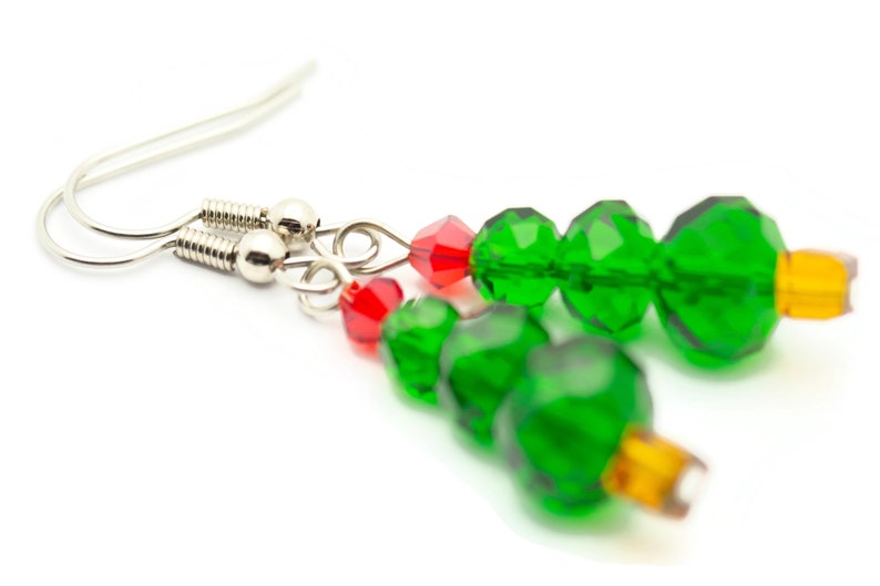 May include: Green and red crystal bead earrings shaped like Christmas trees. The earrings have silver hooks.