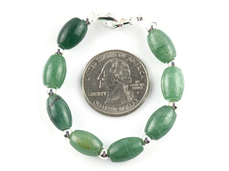 May include: A green jade stone bracelet with silver beads and a silver clasp. The bracelet is about the size of a US quarter.