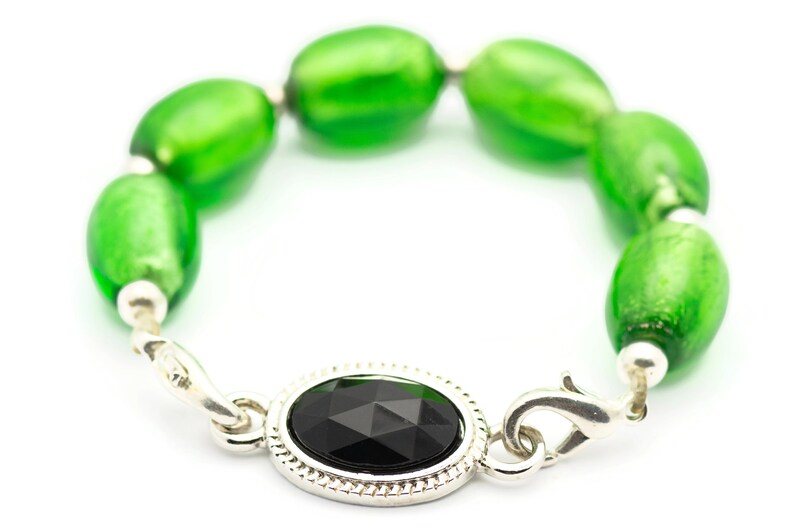 May include: A silver bracelet with a black gemstone and green glass beads.