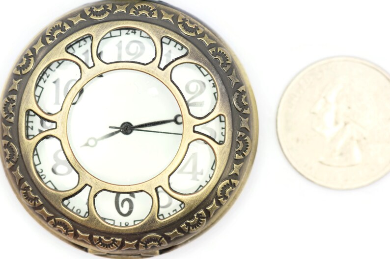 K&ouml;nnte beinhalten: Eine goldfarbene Taschenuhr mit r&ouml;mischen Ziffern auf dem Zifferblatt. Die Uhr hat ein dekoratives, verziertes Design am Rand. Die Uhr ist etwa so gro&szlig; wie eine deutsche 2-Euro-M&uuml;nze.