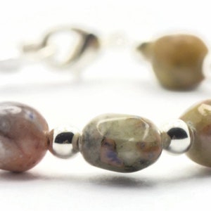 May include: A bracelet made with oval-shaped, multi-colored stones and silver beads.