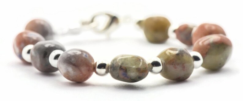 May include: A bracelet made with oval-shaped, multi-colored stones and silver beads.