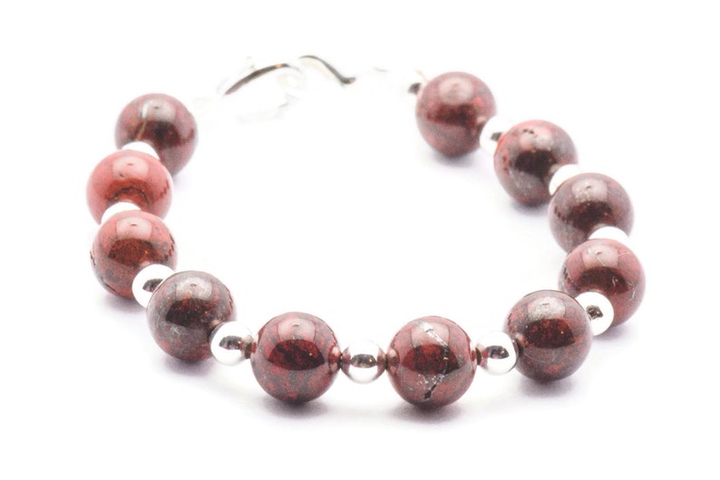 May include: A red and silver beaded bracelet with a silver clasp. The beads are round and have a speckled pattern.