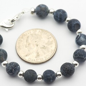 May include: A blue agate bead bracelet with silver spacers and a silver clasp. The bracelet is about the size of a quarter.