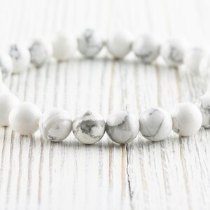 Pode incluir: Pulseira de contas de howlite branca com acabamento liso e polido. As contas s&atilde;o redondas e t&ecirc;m um padr&atilde;o sutil de m&aacute;rmore.