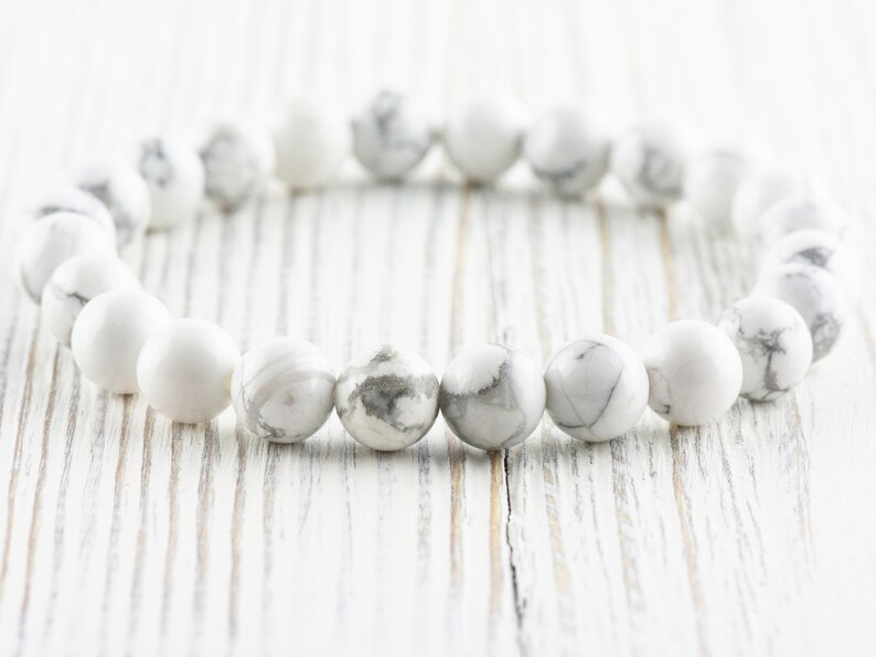 Pode incluir: Pulseira de contas de howlite branca com acabamento liso e polido. As contas s&atilde;o redondas e t&ecirc;m um padr&atilde;o sutil de m&aacute;rmore.