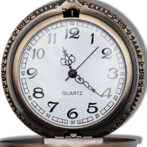 Peut inclure: Une montre de poche de style vintage avec un cadran blanc et des aiguilles noires. La montre a un bo&icirc;tier dor&eacute; et un bracelet en cuir noir. Le cadran de la montre comporte des index horaires en chiffres romains noirs et des index de minutes noirs. La montre est &eacute;galement dot&eacute;e d'un mouvement &agrave; quartz.