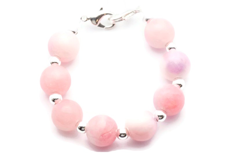 Puede incluir: Pulsera de cuentas con cuentas redondas de color rosa claro y blanco. Las cuentas est&aacute;n ensartadas con peque&ntilde;as cuentas de metal plateado. La pulsera tiene un cierre plateado.