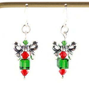 Pode incluir: Brincos de prata com um design de la&ccedil;o e cubo de cristal verde e vermelho. Os brincos est&atilde;o em um expositor.