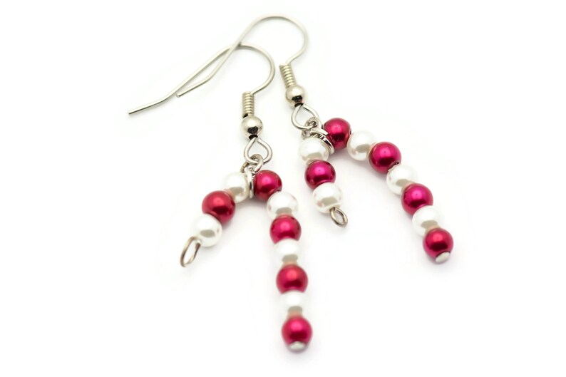 May include: A pair of silver earrings with red and white beads, shaped like candy canes.