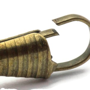 Pode incluir: Um fecho de metal dourado com um design texturizado e estriado. O fecho tem um fecho de gancho e la&ccedil;o.