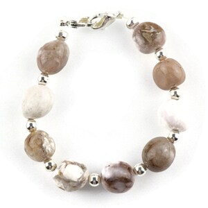 May include: A bracelet made with brown, white, and gray agate beads and silver spacers.