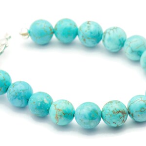 May include: A turquoise beaded bracelet with a silver clasp. The beads are round and have a marbled pattern.