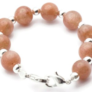 May include: A bracelet with a silver clasp and round, light brown beads.
