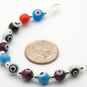 Puede incluir: Un brazalete de plata con una variedad de cuentas de vidrio de colores. Las cuentas presentan un dise&ntilde;o de ojo malvado con acentos negros y blancos. El brazalete tiene un cierre de plata.