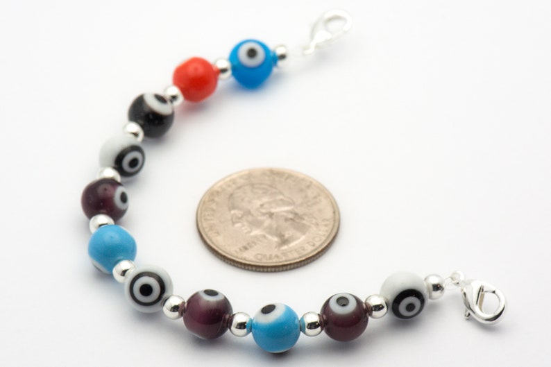 Puede incluir: Un brazalete de plata con una variedad de cuentas de vidrio de colores. Las cuentas presentan un dise&ntilde;o de ojo malvado con acentos negros y blancos. El brazalete tiene un cierre de plata.
