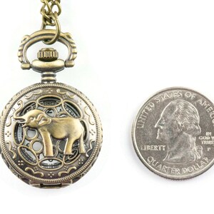 May include: A bronze pocket watch with an elephant design on the face. The watch is about the size of a US quarter.