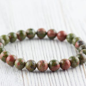 May include: A green and red speckled stone bracelet with round beads.