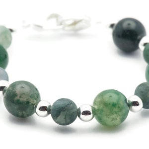 May include: A green agate gemstone bracelet with silver beads. The bracelet is made with round, polished stones and has a silver clasp.