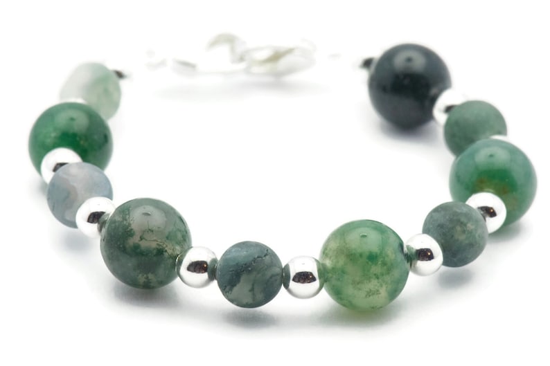 May include: A green agate gemstone bracelet with silver beads. The bracelet is made with round, polished stones and has a silver clasp.