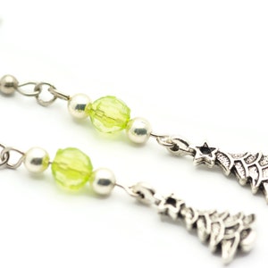 May include: Silver dangle earrings with green glass beads and silver Christmas tree charms.