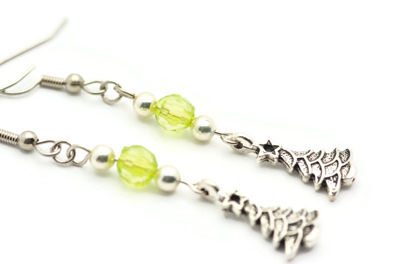 May include: Silver dangle earrings with green glass beads and silver Christmas tree charms.