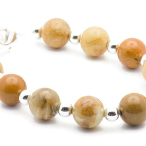 May include: A bracelet made with brown and beige agate beads and silver spacers.