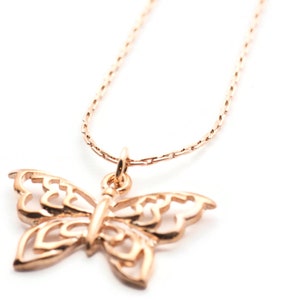 Peut inclure: Un collier d&eacute;licat en or rose avec un pendentif en forme de papillon. Le papillon est finement con&ccedil;u avec un motif d&eacute;coup&eacute;.