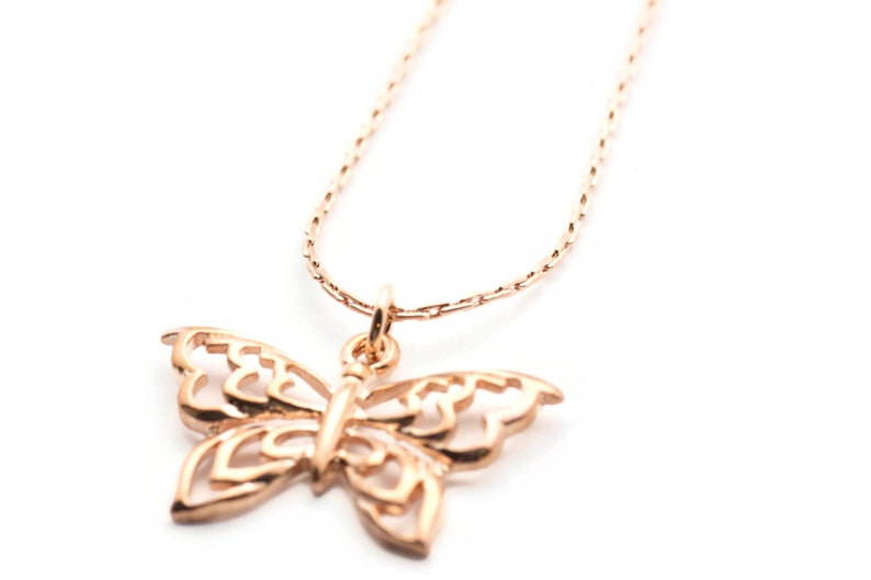 Peut inclure: Un collier d&eacute;licat en or rose avec un pendentif en forme de papillon. Le papillon est finement con&ccedil;u avec un motif d&eacute;coup&eacute;.