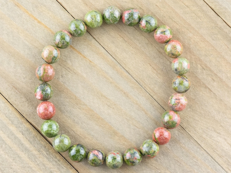 May include: A green, pink, and brown gemstone bracelet with round beads.