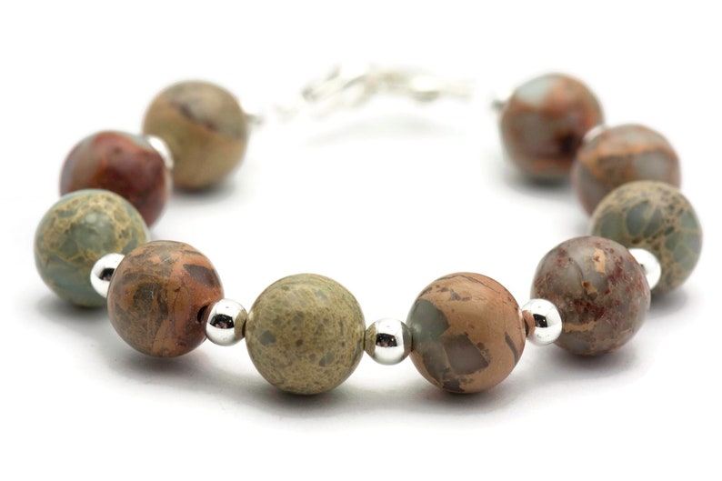 May include: A bracelet made with brown, green, and white patterned beads separated by silver beads.