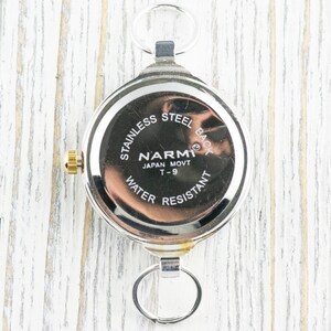 Pu&ograve; includere: Un orologio da tasca argentato con corona dorata e retro in acciaio inossidabile. Presenta anelli per il fissaggio in alto e in basso. Il retro reca la scritta "STAINLESS STEEL BACK", "NARMI JAPAN MOVT T-9" e "WATER RESISTANT".