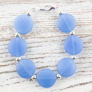 Peut inclure: Un bracelet de perles en verre givr&eacute; bleu clair avec des perles d'espacement argent&eacute;es et un fermoir argent&eacute;.