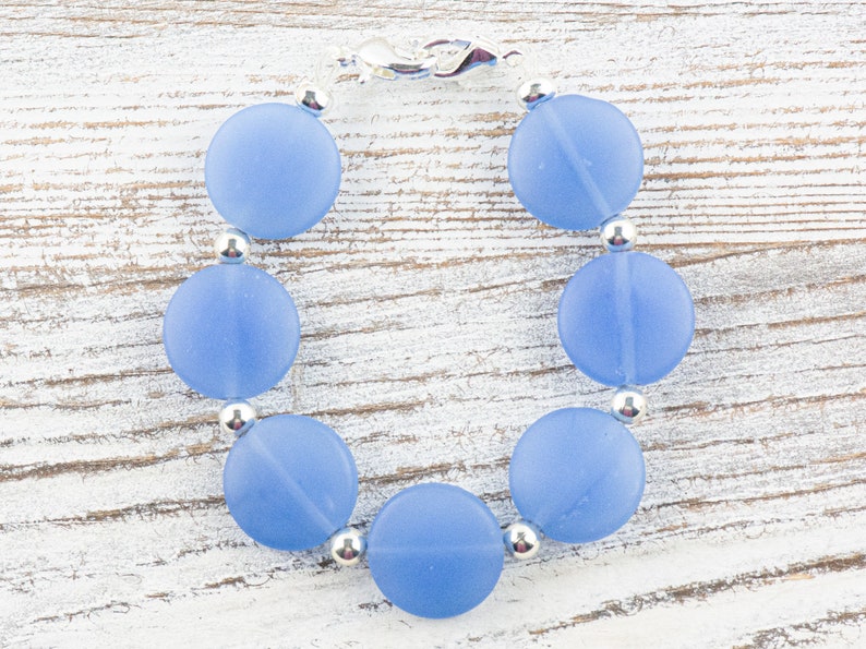 Peut inclure: Un bracelet de perles en verre givr&eacute; bleu clair avec des perles d'espacement argent&eacute;es et un fermoir argent&eacute;.