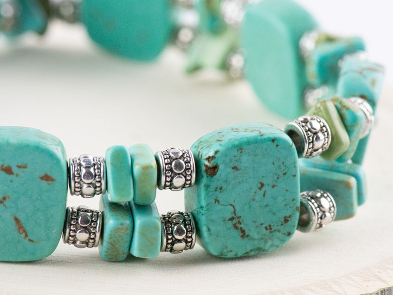 Op de afbeelding: Een turquoise en zilveren armband met vierkante turquoise kralen en zilveren spacer kralen.