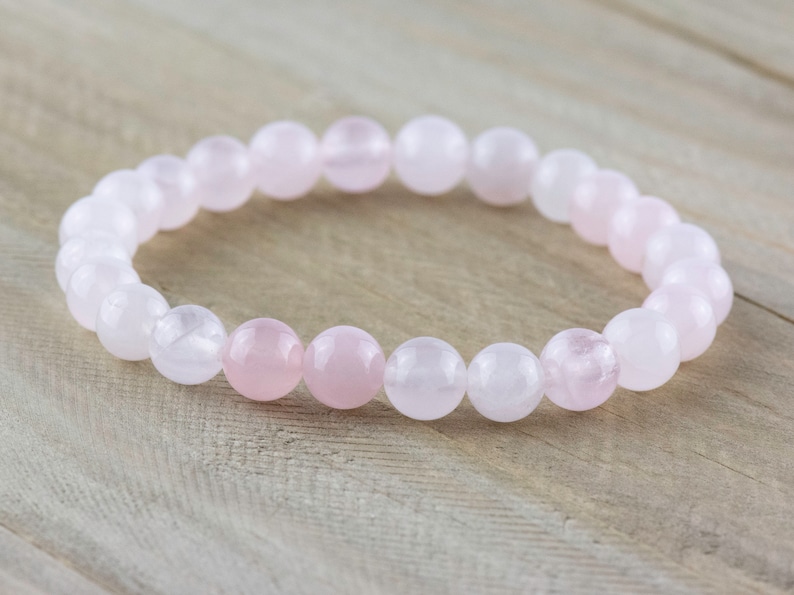 May include: A pink and white gemstone bracelet with round beads. The bracelet is made of rose quartz.