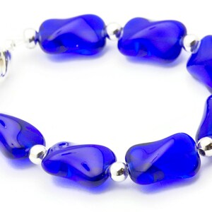 Pode incluir: Um bracelete de contas de vidro azul com detalhes prateados. O bracelete &eacute; feito de contas de forma irregular e tem um fecho de encaixe.
