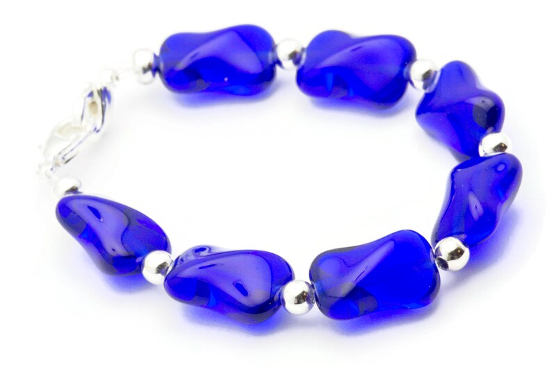 Pode incluir: Um bracelete de contas de vidro azul com detalhes prateados. O bracelete &eacute; feito de contas de forma irregular e tem um fecho de encaixe.