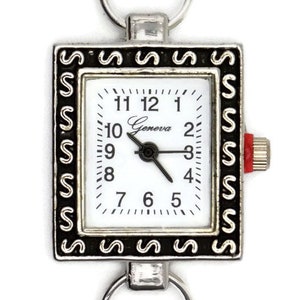Könnte beinhalten: Eine silberne Taschenuhr mit einem schwarzen und silbernen Rahmen. Das Zifferblatt der Uhr ist weiß mit schwarzen Zahlen und Zeigern. Die Uhr hat einen Schlüsselring.