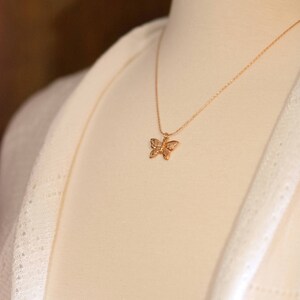 Peut inclure: Un collier avec un pendentif en forme de papillon dor&eacute; sur un mannequin blanc.