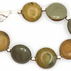 May include: A bracelet made with round, green and brown jasper stones and silver beads. The bracelet has a silver clasp.