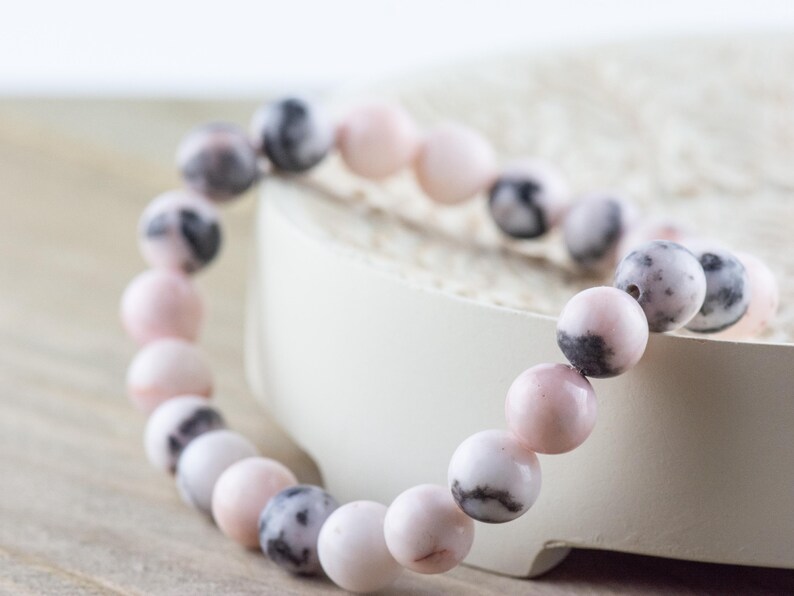 May include: A pink and black gemstone bracelet with round beads. The bracelet is made of natural stones and is a beautiful and unique piece of jewelry.