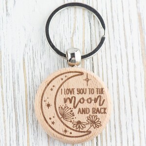 May include: Wooden keychain with a crescent moon design and the text "I love you to the moon and back".