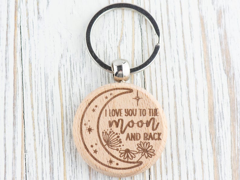 May include: Wooden keychain with a crescent moon design and the text "I love you to the moon and back".