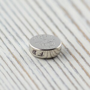 Pu&ograve; includere: Una batteria per orologio argentata con il testo "392/1.5V  Made in Japan  LR44  AG13  GP" stampato sulla parte superiore.